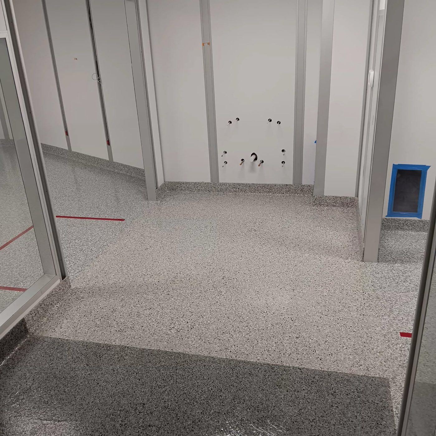 Seamless gray flake clean room floor with flush red LED demarcation lines dividing contamination-control zones